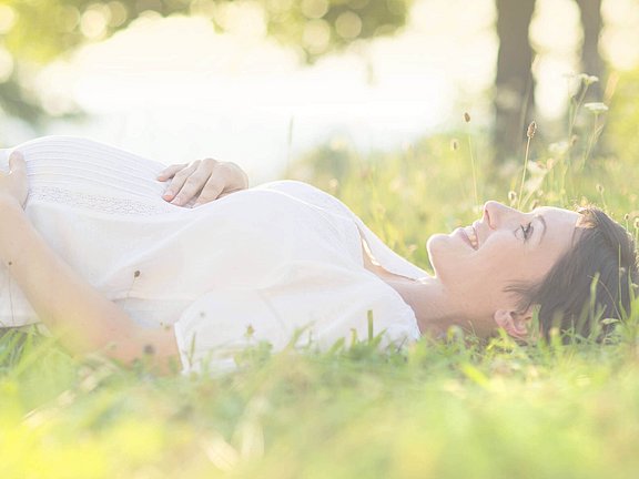 Eine schwangere Frau liegt unbesorgt im Gras nach einem negativen Allergietest
