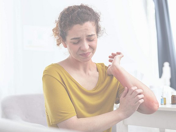 Frau juckt sich am Arm nach allergischer Reaktion und braucht Hilfe vom Allergologen in der Nähe