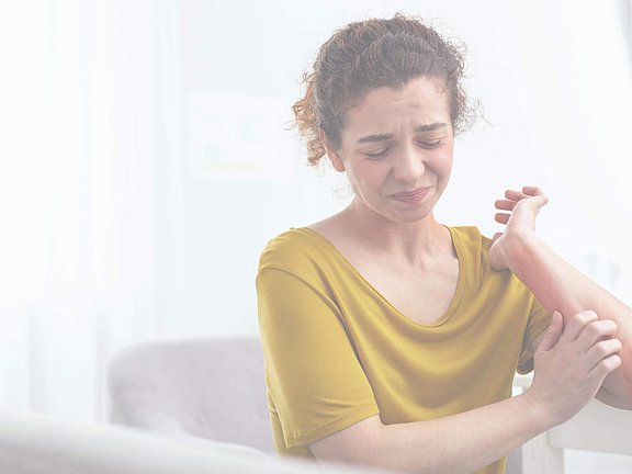 Frau juckt sich am Arm nach allergischer Reaktion und braucht Hilfe vom Allergologen in der Nähe