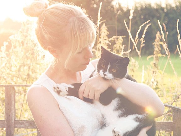 Eine Frau hält ihre schwarze Katze nach behandelter Katzenallergie im Arm
