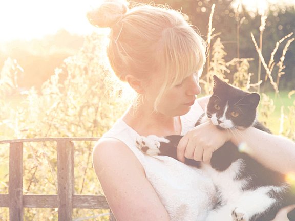Eine Frau hält ihre schwarze Katze nach behandelter Katzenallergie im Arm