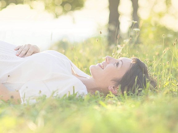 Eine schwangere Frau liegt unbesorgt im Gras nach einem negativen Allergietest
