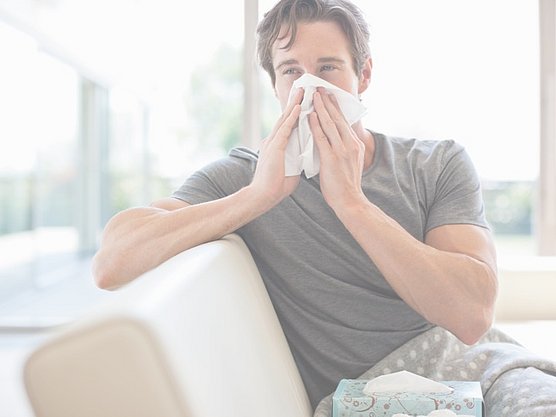 Mann mit Allergie-Symptomen putzt sich seine Nase. Symptome richtig deuten.