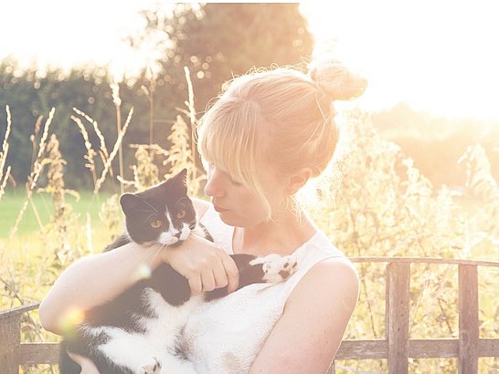 Eine Frau hält ihre schwarze Katze nach behandelter Katzenallergie im Arm.